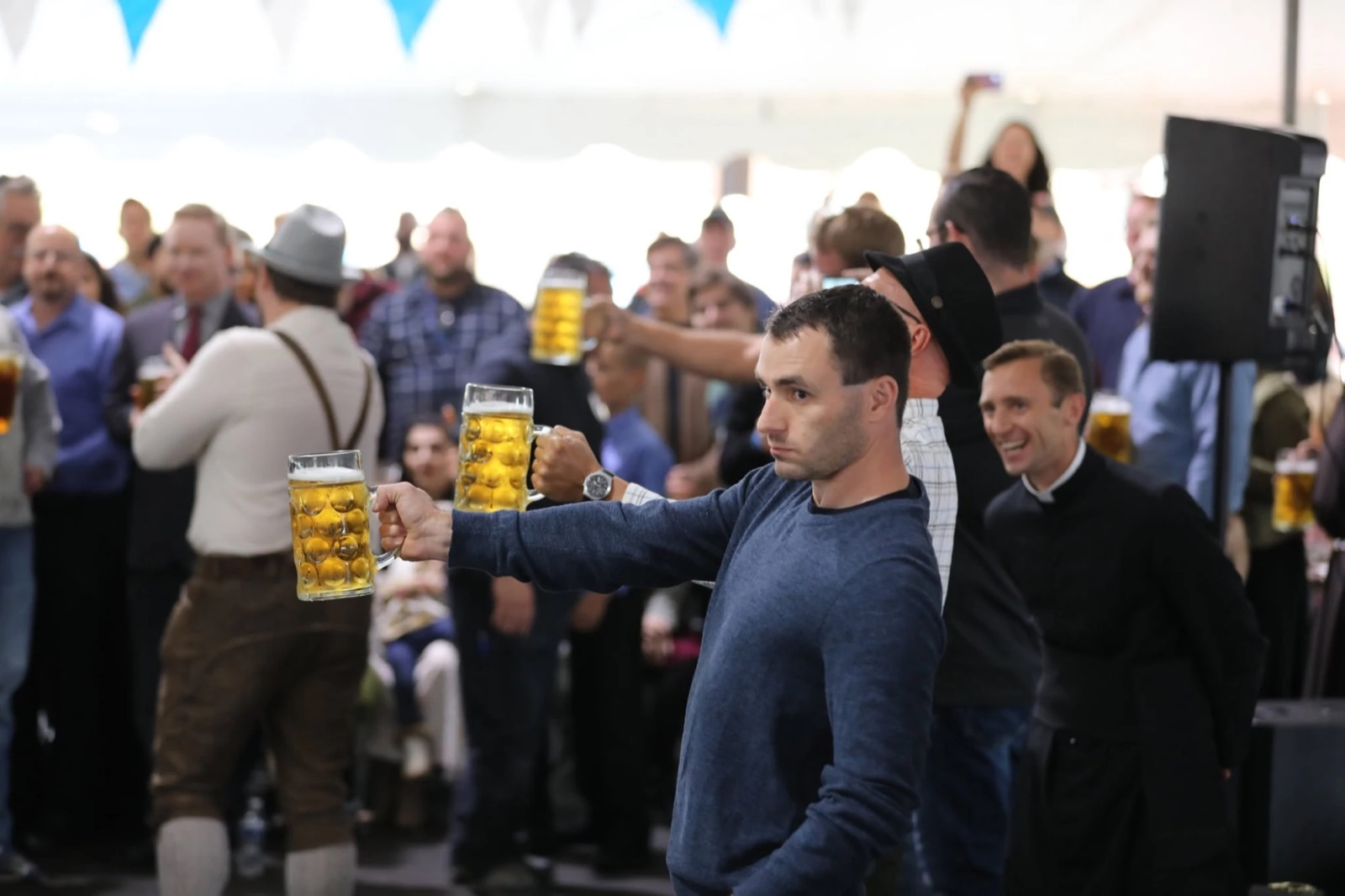 Nick Soltysiak holding a full stein at arm's length as the Canon smiles behind him