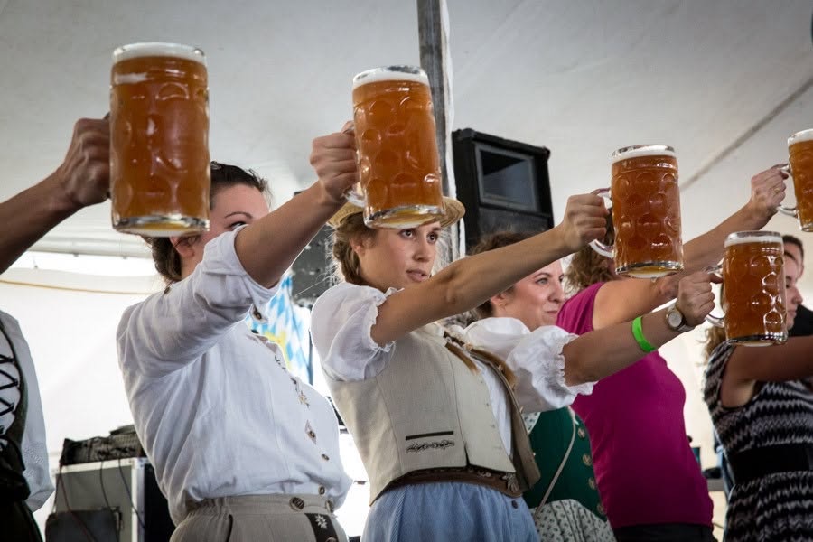 Women in dirndls holding full liter steins at arm's length