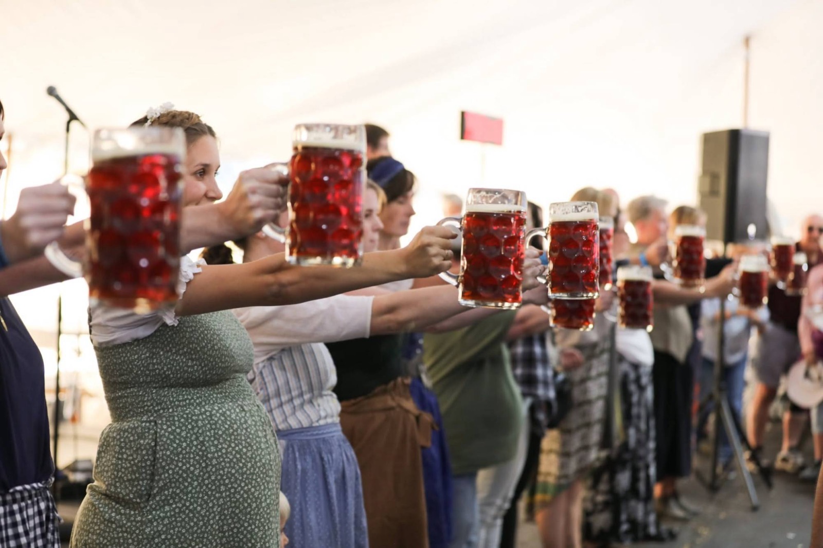 Women competitors holding dark beer steins in a line