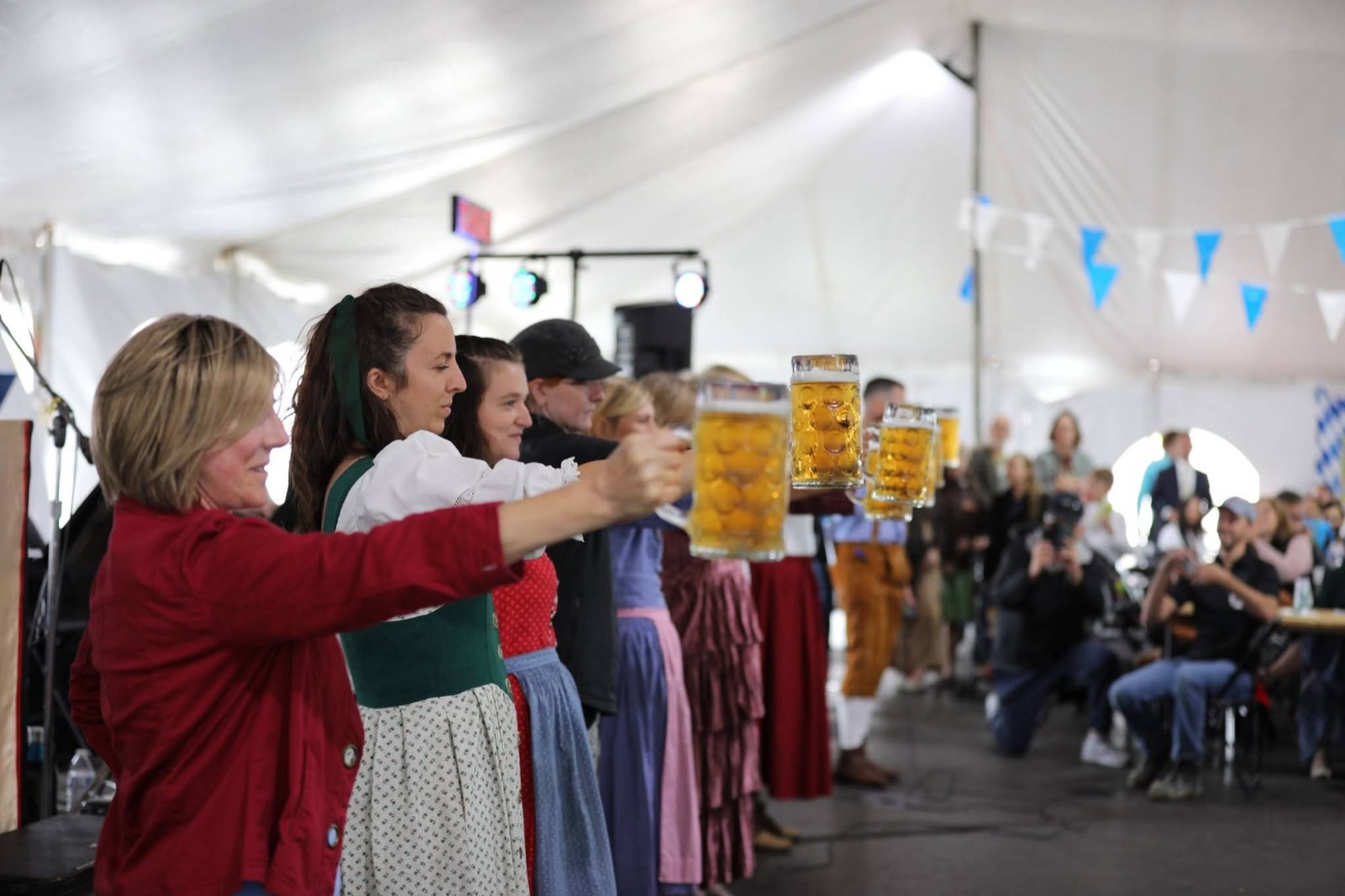 The women's line holding steins at arm's length under the tent