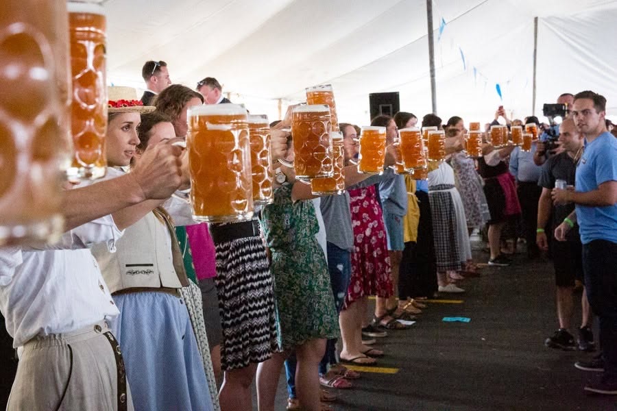 Women in dirndls holding steins in a long line